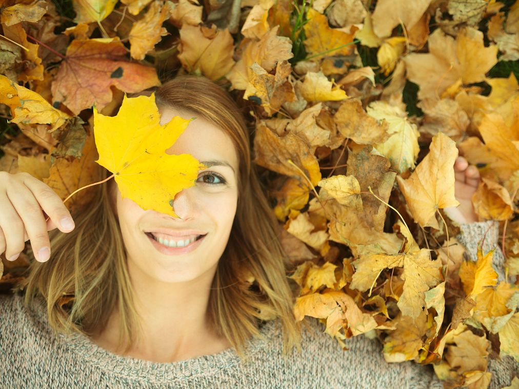 femme souriante dans les feuilles d'automne
